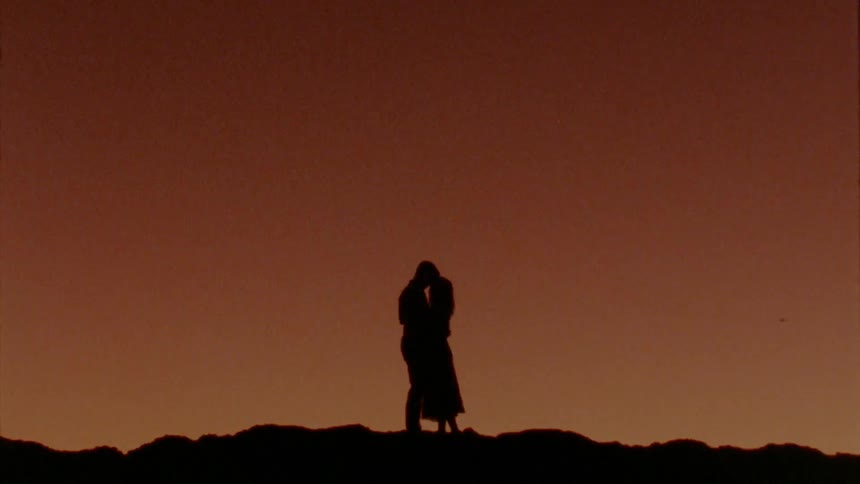 Couple hugging ontop of a hill