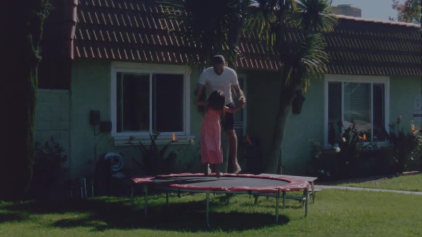 A father and daughter jumping on a trampoline