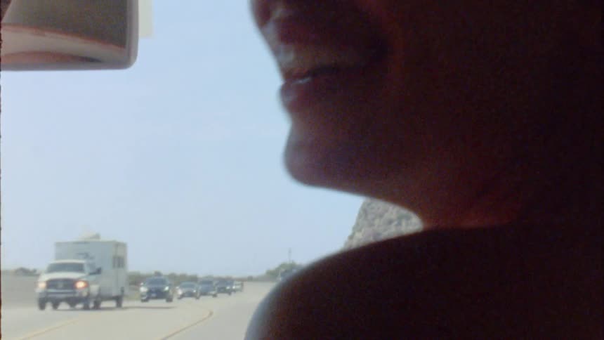 A woman in the passenger seat laughs as she shimmies looking at the backseat