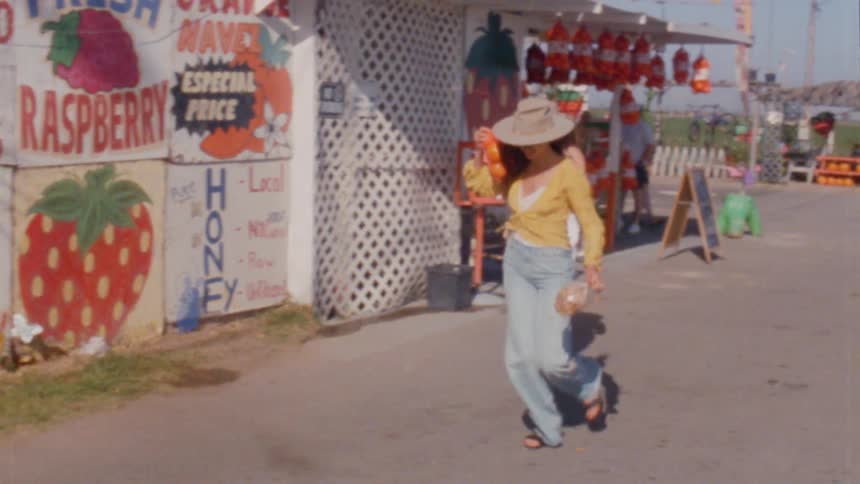 Two women carry fruit they purchased from a street vendor
