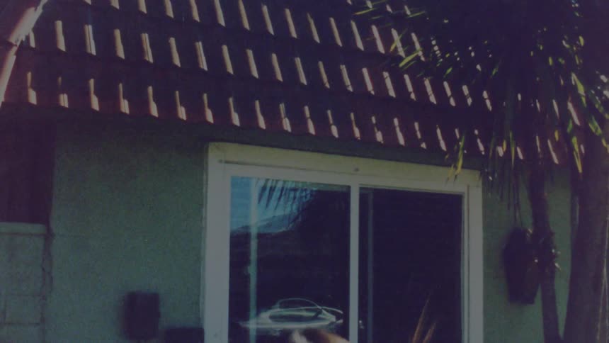Young girl wearing a pink dress jumping over a trampoline in the porch at home