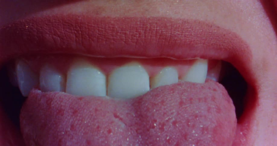 Close up of a person sticking their tongue out an then biting down on it