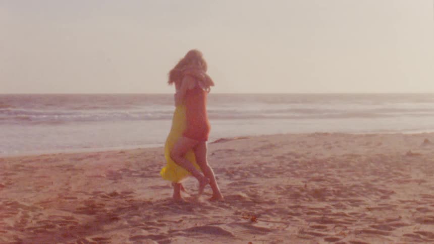 Two girls are dancing and hugging on a beach