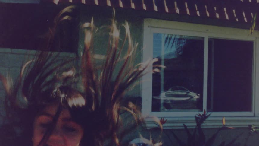 Girl wearing a pink dress jumping over a trampoline on the porch at home