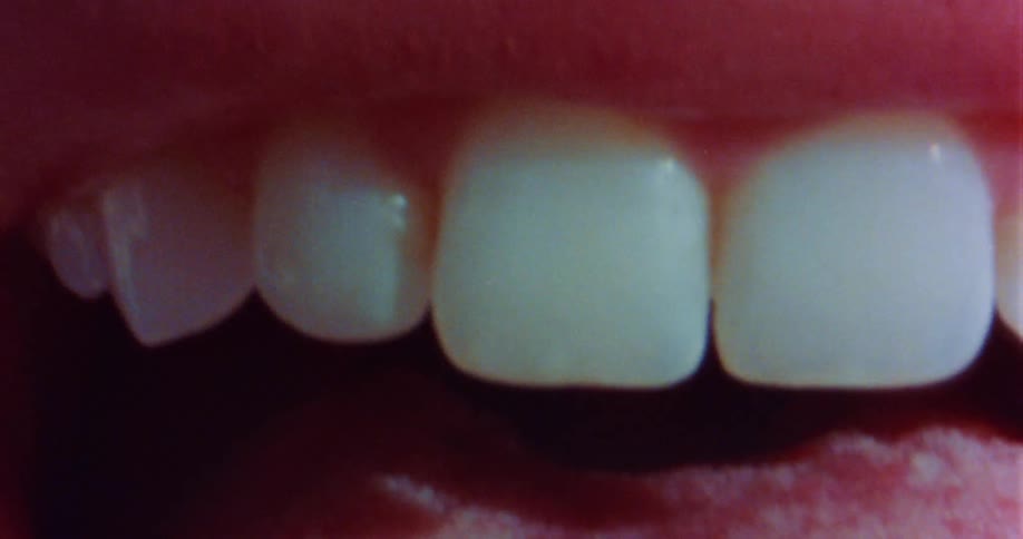 A woman is sticking her tongue out of her mouth and holding it against her teeth