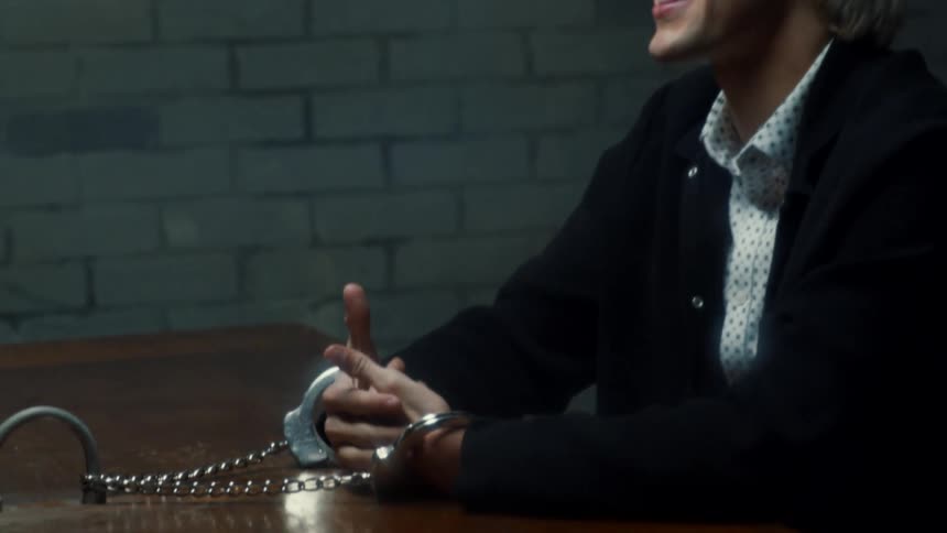 A man handcuffed to a table talks