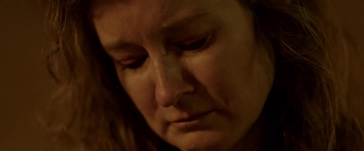 Tears glisten on a womans lashes as she looks down distraught