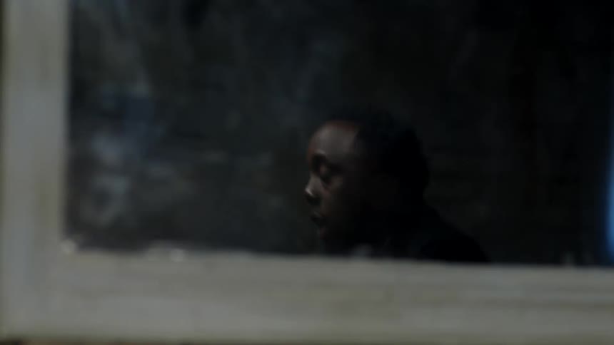 Man sitting at a table talking to someone else seen from a window
