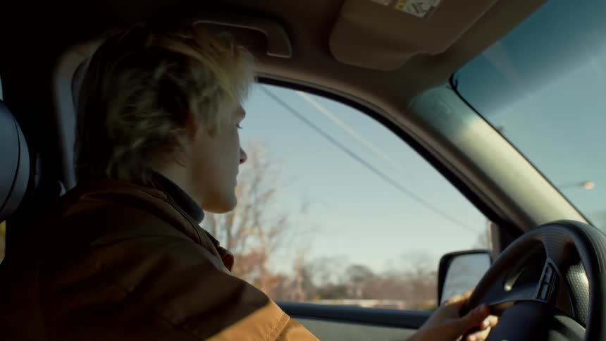 A man is driving a vehicle on a road in the fall