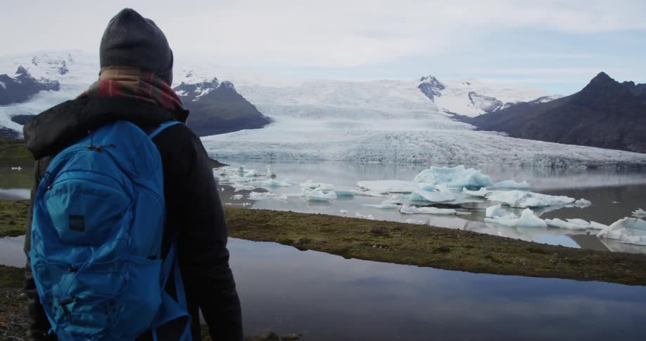 A person stands near a valley covered with ice