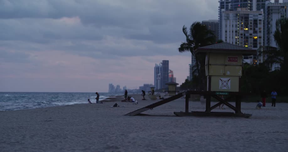 People are walking on a beach with heavy waves hitting the shore