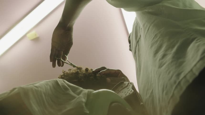 Hair falls to the floor as a barber cuts and trims with scissors