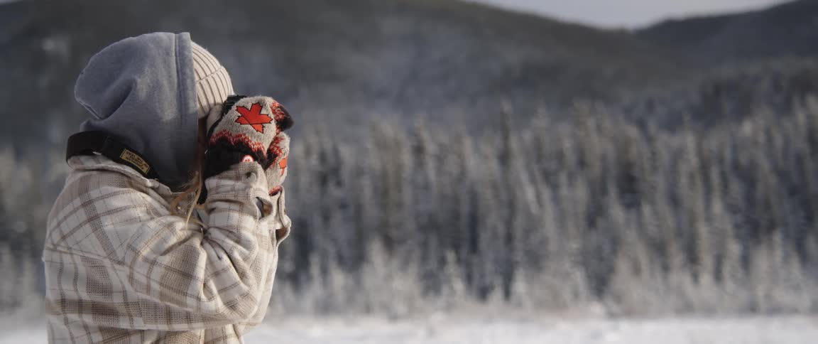Young woman takes pictures near a pine tree forest on the mountains at winter