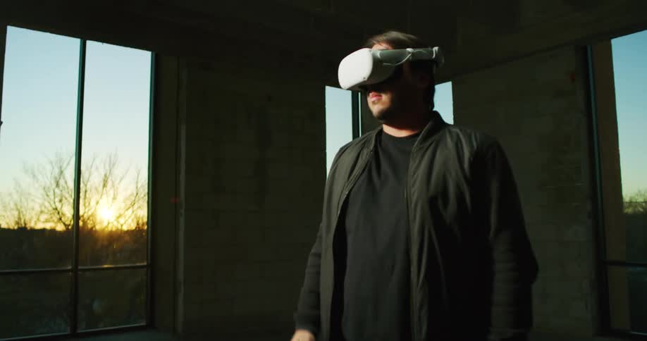 A man in a room putting on virtual reality headset then turning around