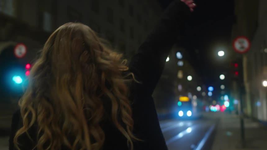 Young blonde woman walking on the city street at night