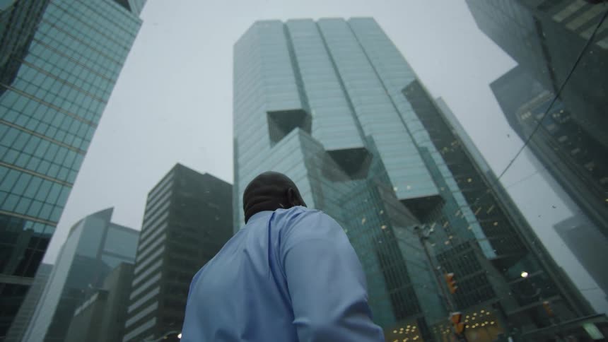 A man runs through downtown with his briefcase as snow falls