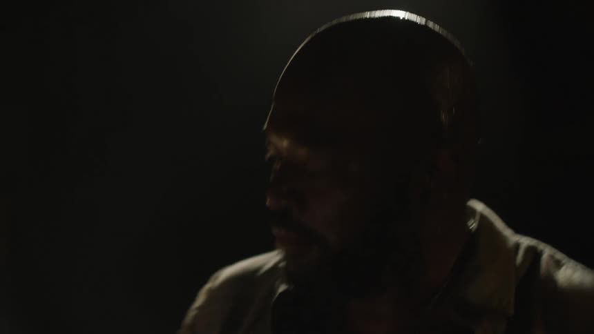 A man plays the drums in a dark room