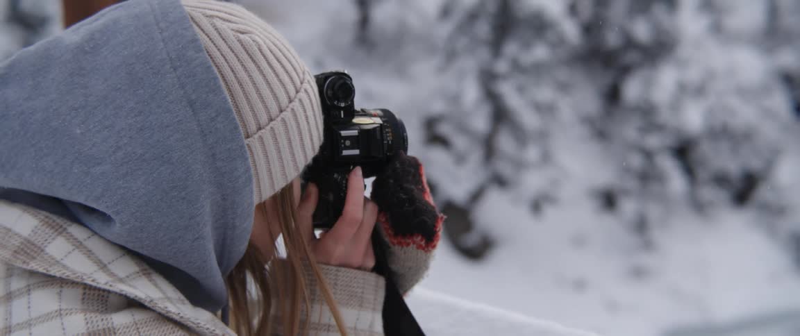 Young woman takes pictures using a camera in the mountains at winter