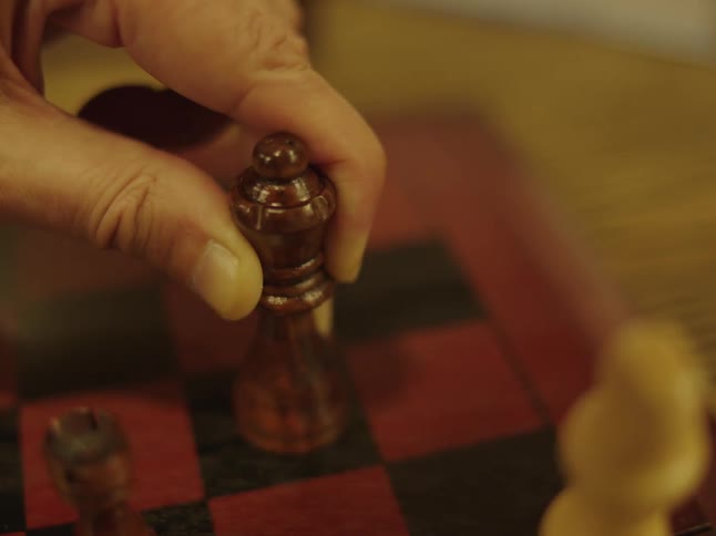 A man moves a chess piece across the board