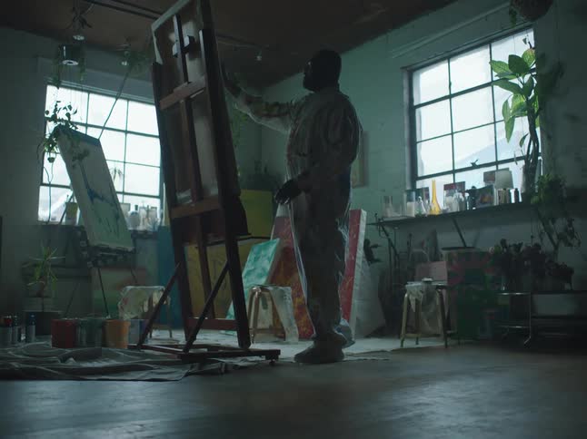 A man is painting on a canvas indoors
