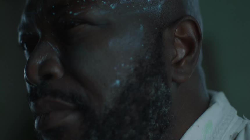 A strobe light flashes on the face of a black man