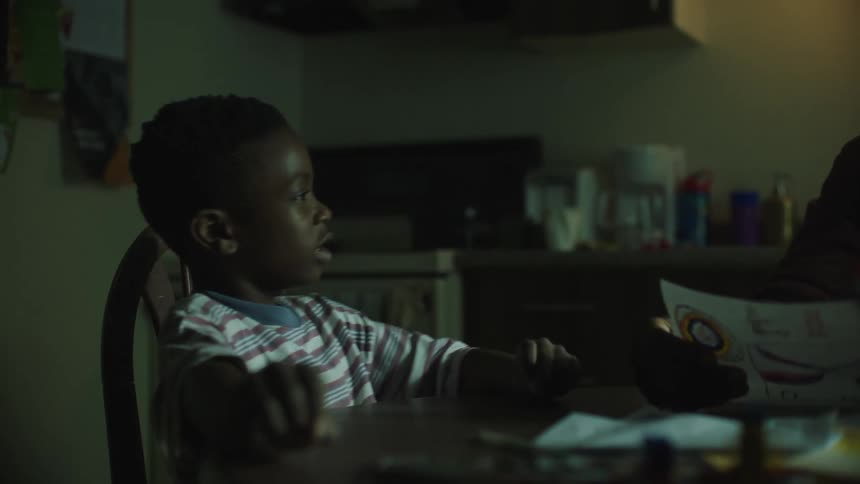 A boy talks to an adult while sitting at a kitchen table