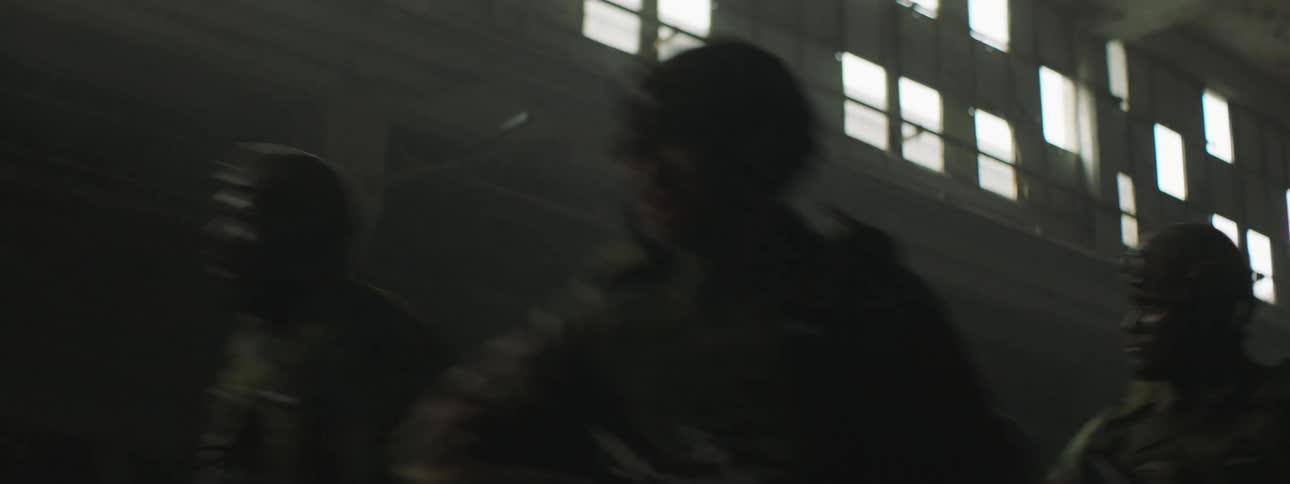 The soldiers run through the dark warehouse