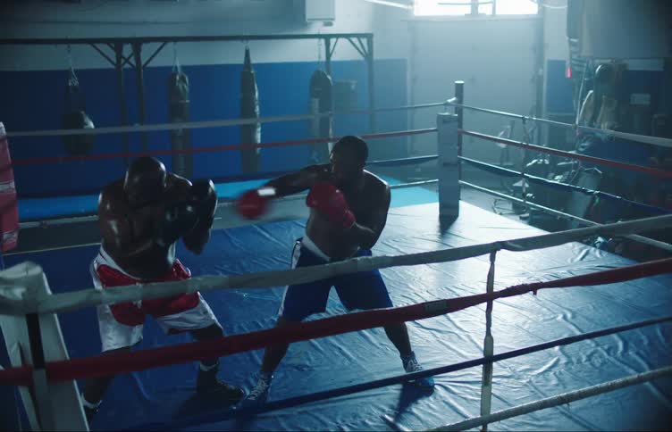 Two men in a gym practicing boxing together