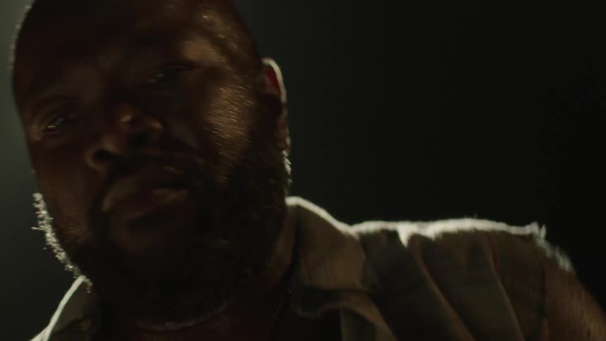 Drummer plays drums vigorously while sweating directly under a stage light