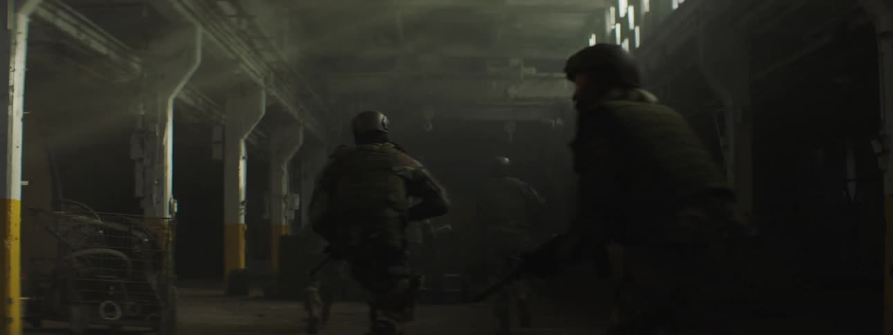 Soldiers run into a parking garage with their rifles drawn