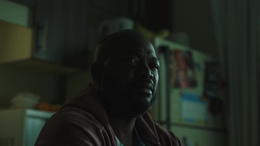 A man is sitting at a table in his kitchen