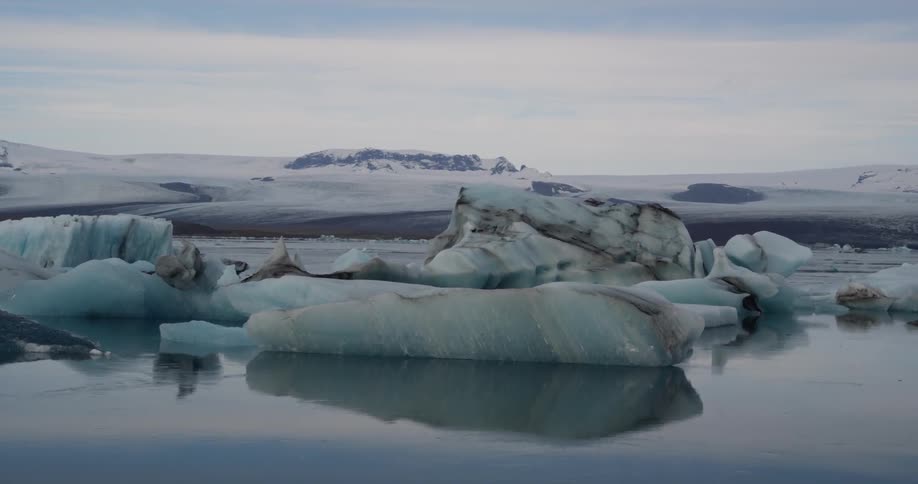 Blue ice floats in the water near the shore