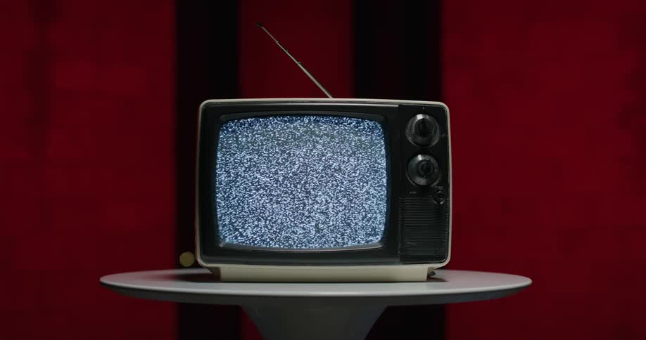 Television with fuzzy screen on round table in front of red background