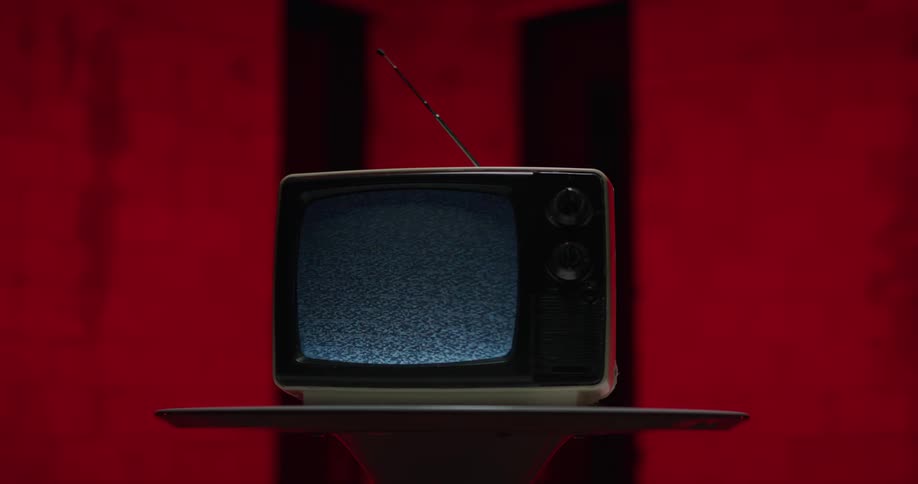 Vintage television over a small table inside a room shows static on the screen