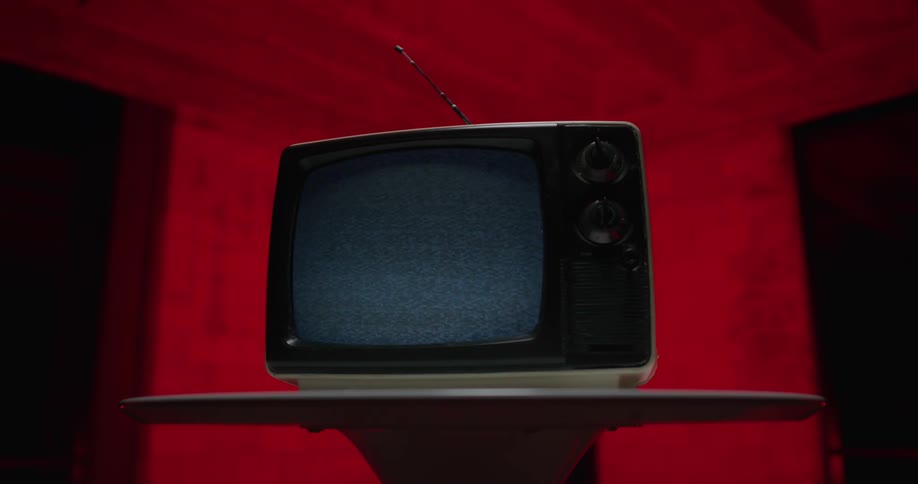 A portable television is sitting on a table and static is on the screen