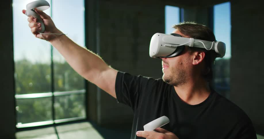 A man uses controllers while wearing a virtual reality headset