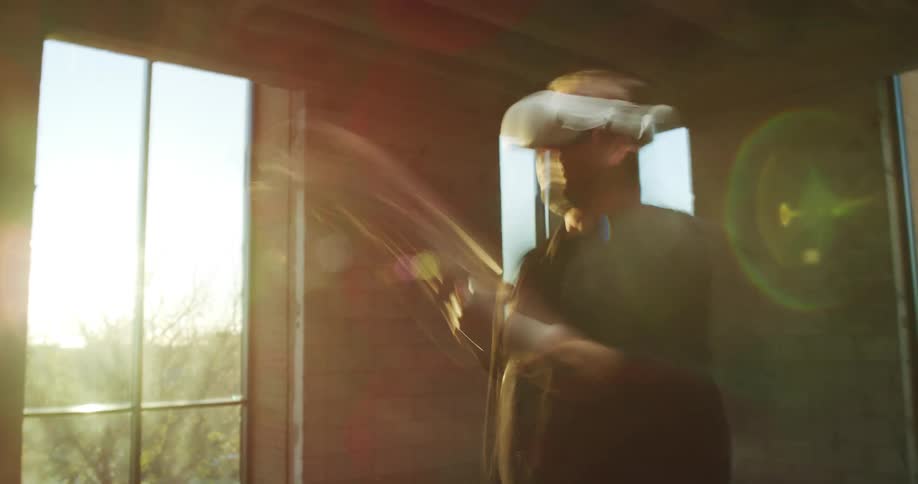 A man swings the controllers while using virtual reality