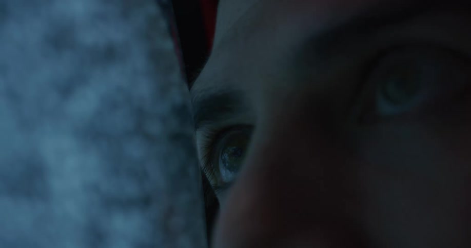 Close up of the face of a man leaning on the screen of a vintage television showing static