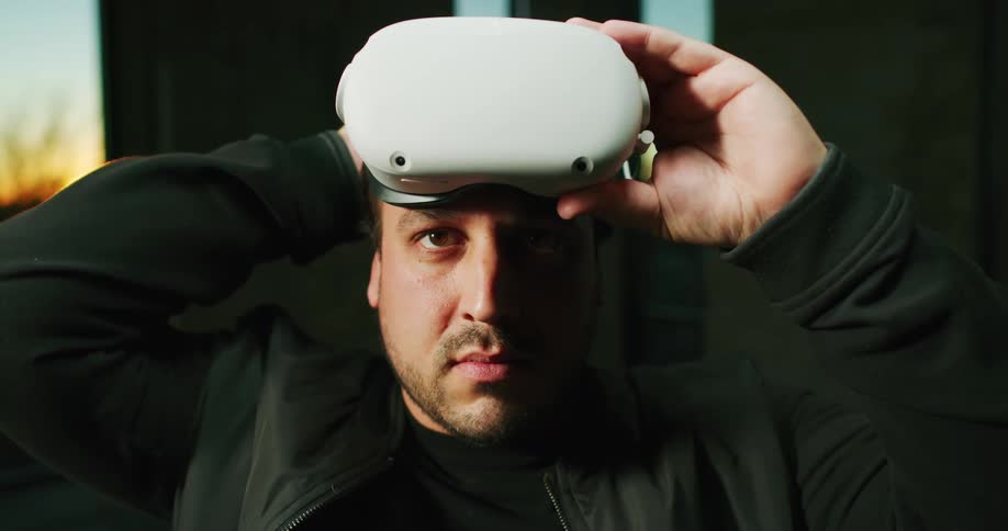 Young man wearing virtual reality goggles over his forehead looking at the camera