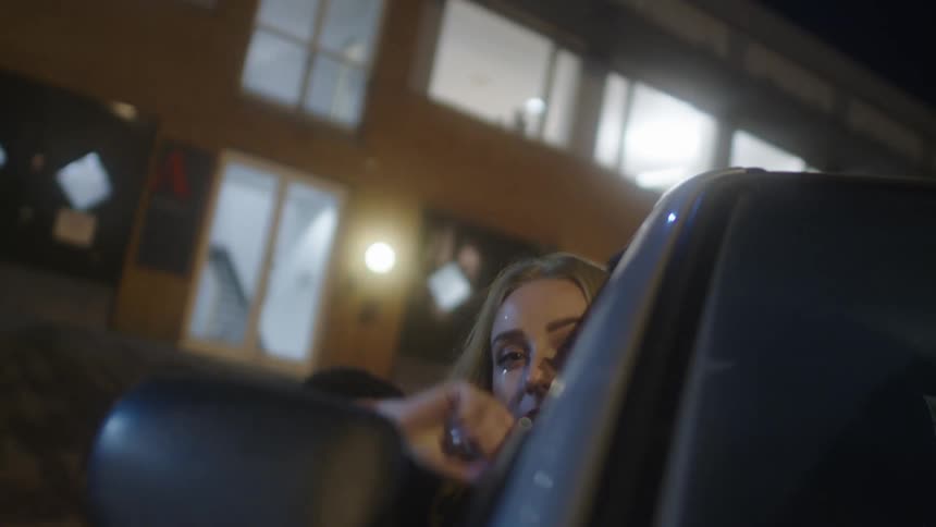 A woman waves her arm out of the moving car