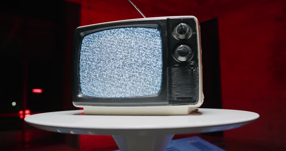 Vintage television over a small round table inside a room at night