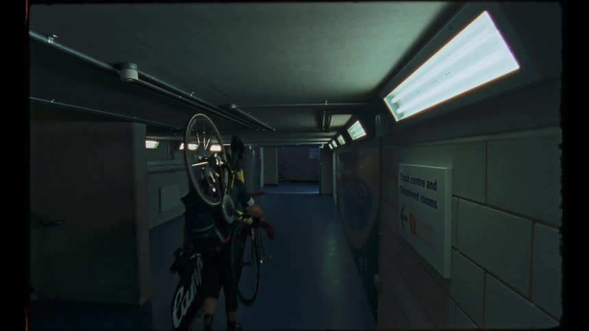 A man is carrying a bicycle down a long corridor
