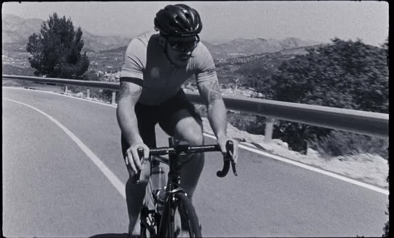Footage of a man riding a bicycle on a road near mountains