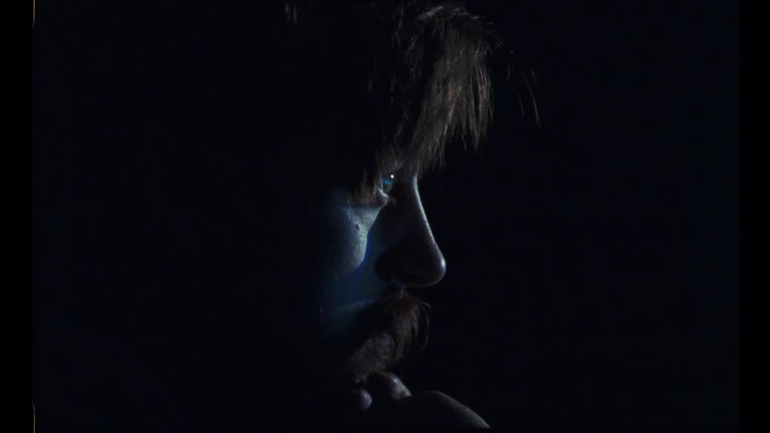 A man stares ahead as a screen reflects light on his face