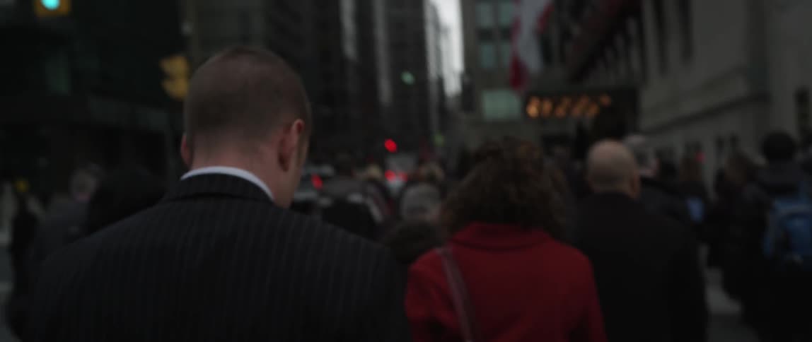 A large crowd of people are traveling on a city sidewalk