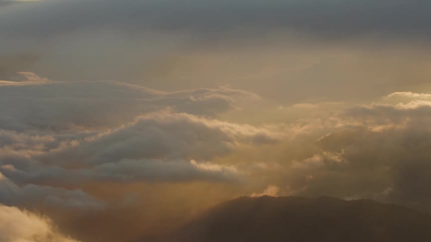 Tight shot of sunset clouds high above from commercial jetliner
