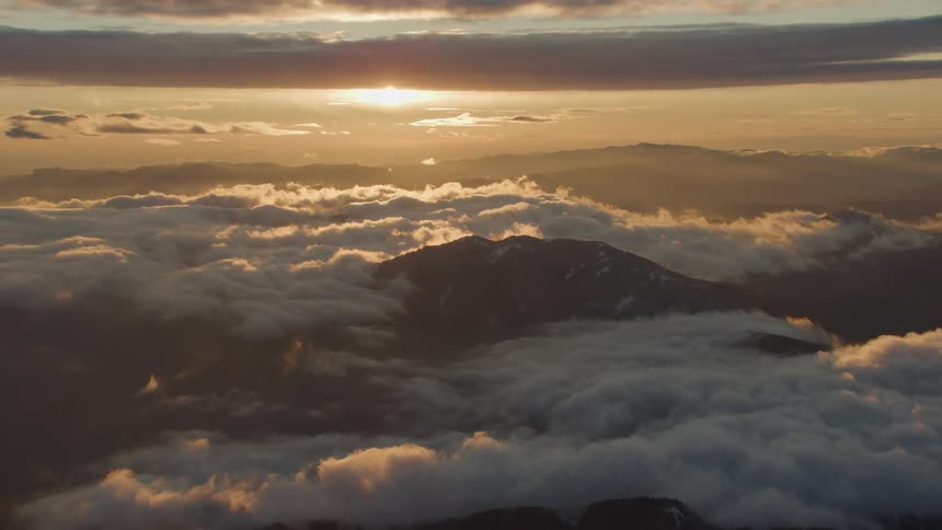 Aerial view of mountain above clouds at sunset