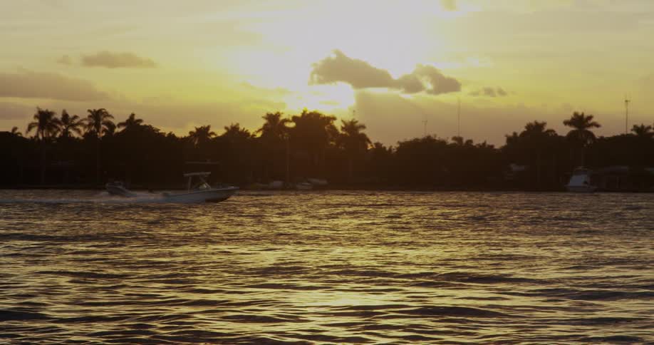 A boat moves through some waters at sunset