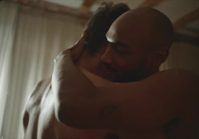 Shirtless men holding each other dances in living room at home