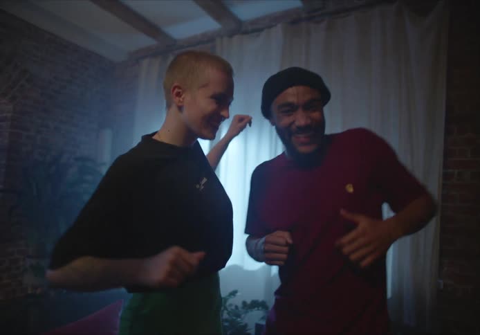 A group of friends laugh as they dance around their living room